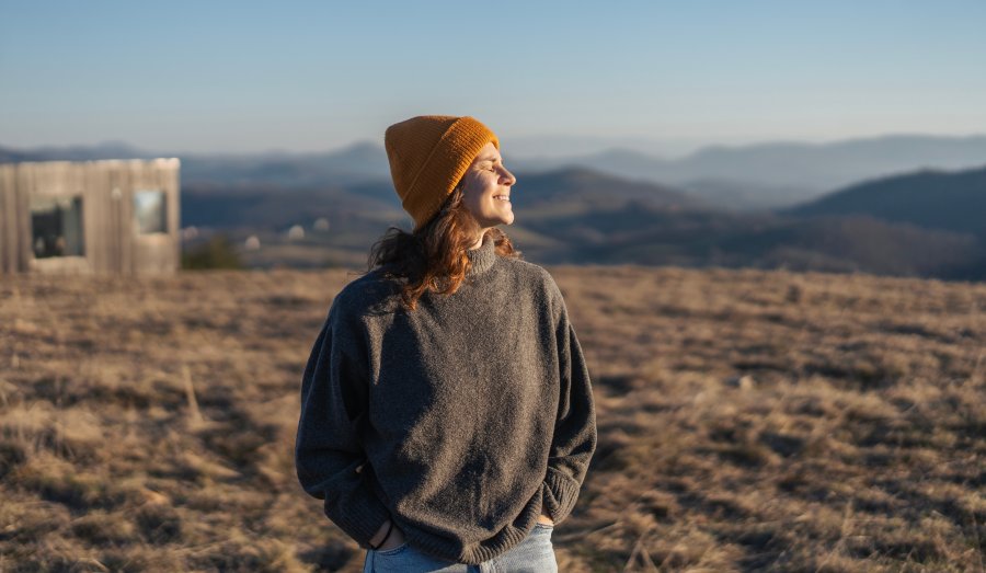 Donna in un paesaggio naturale che si ferma a respirare, simbolo di lentezza e tempo vissuto