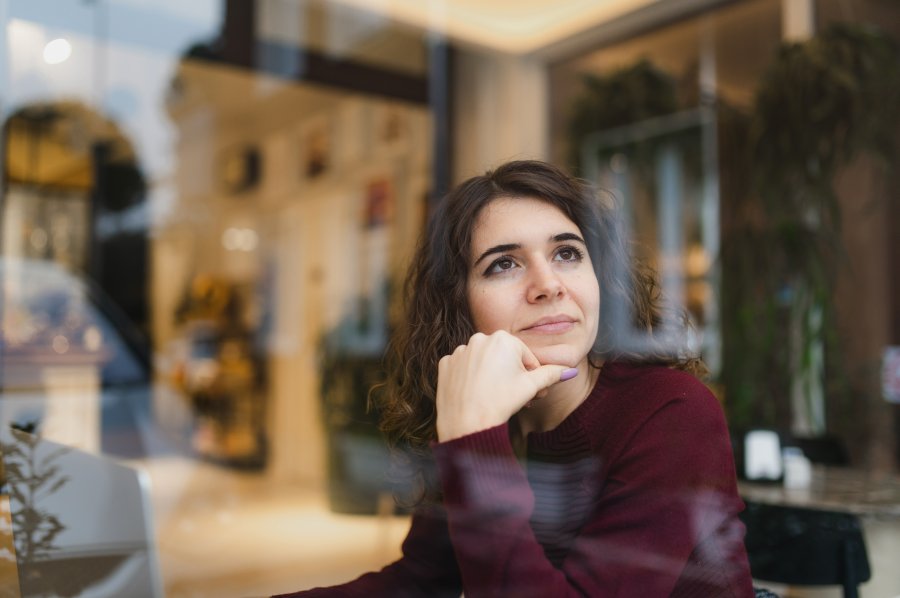 Donna seduta vicino a una finestra in un ambiente interno.
