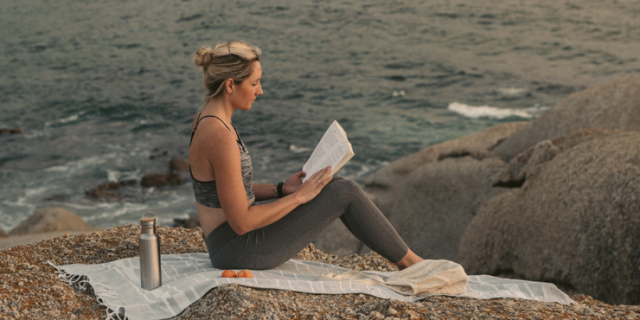 Persona che legge un libro davanti a un paesaggio italiano estivo